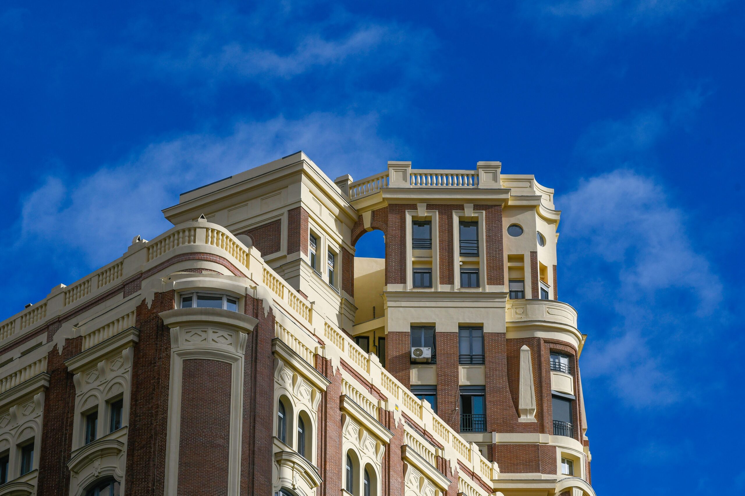 A low-angle shot of a beautiful architectural building under a blue sky with clouds in Madrid, Spain.